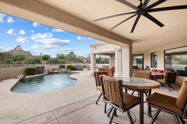 view of swimming pool featuring pool water feature, a mountain view, ceiling fan, and a patio area