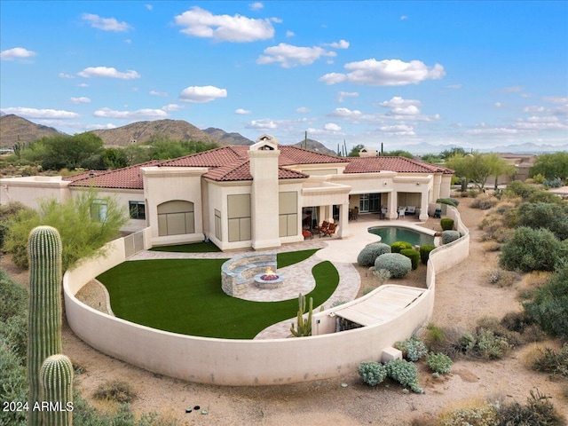 rear view of house with a mountain view, a patio area, and a yard