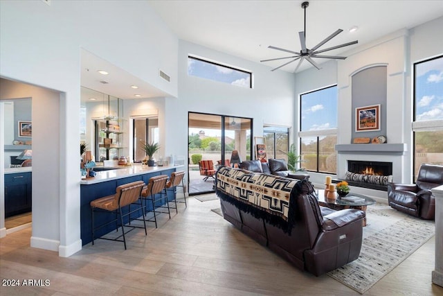 living room featuring light wood-type flooring, a healthy amount of sunlight, a fireplace, and ceiling fan