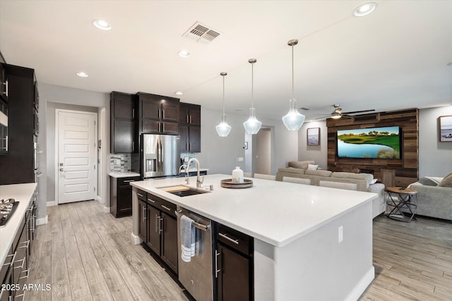 10702 E Sheffield Dr, Mesa, AZ 85212 - kitchen with sink, hanging light fixtures, light wood-type flooring, stainless steel appliances, and a kitchen island with sink