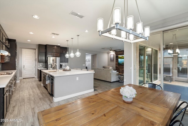 10702 E Sheffield Dr, Mesa, AZ 85212 - kitchen featuring appliances with stainless steel finishes, hardwood / wood-style floors, sink, dark brown cabinetry, and a center island with sink