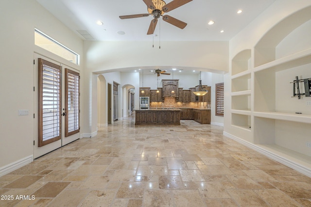 interior space with a towering ceiling, stone tile floors, arched walkways, and baseboards