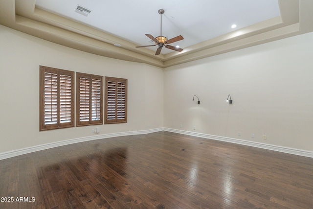 spare room featuring baseboards, a tray ceiling, and wood finished floors