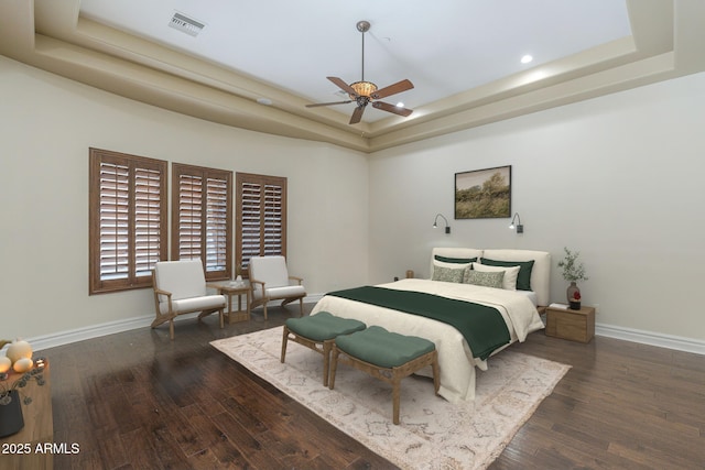 bedroom featuring wood finished floors, a raised ceiling, visible vents, and baseboards