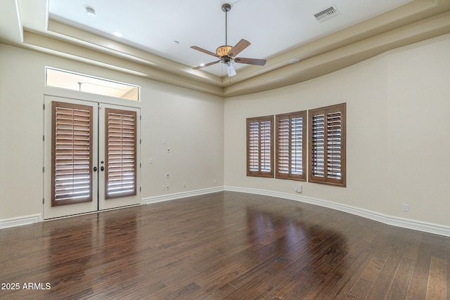 unfurnished room with wood finished floors, a ceiling fan, visible vents, baseboards, and a raised ceiling