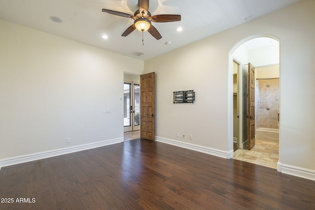 unfurnished room with arched walkways, baseboards, and wood finished floors