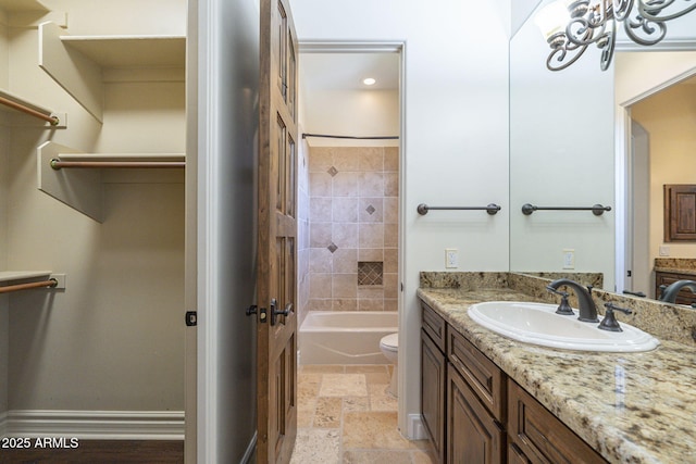 bathroom with  shower combination, stone tile floors, vanity, and toilet