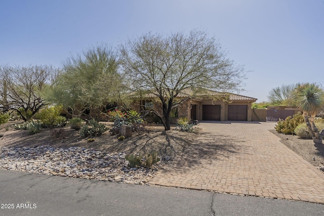 view of front of property featuring a garage, a tile roof, a gate, fence, and decorative driveway