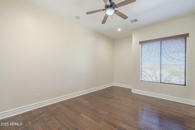 empty room with baseboards, visible vents, and dark wood finished floors