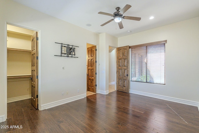 unfurnished bedroom with baseboards, a walk in closet, wood finished floors, and recessed lighting