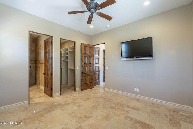 unfurnished bedroom with a walk in closet, recessed lighting, a closet, a ceiling fan, and baseboards