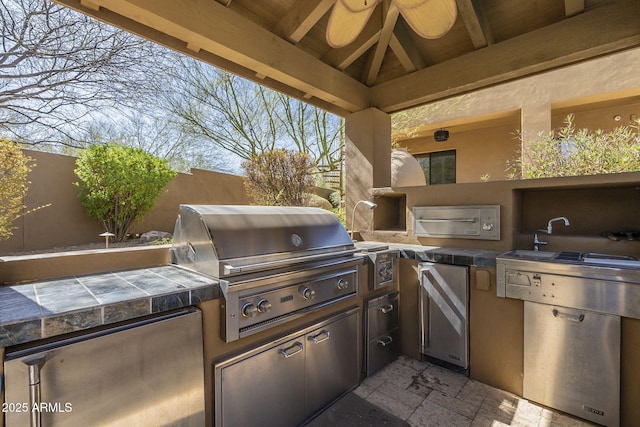 view of patio / terrace with an outdoor kitchen, grilling area, fence, and a gazebo