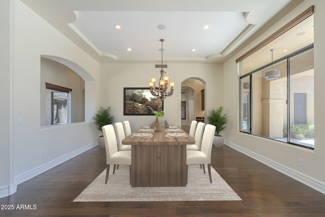 dining room with a notable chandelier, baseboards, a raised ceiling, and dark wood-style flooring