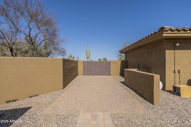 exterior space with a gate, a tile roof, and stucco siding