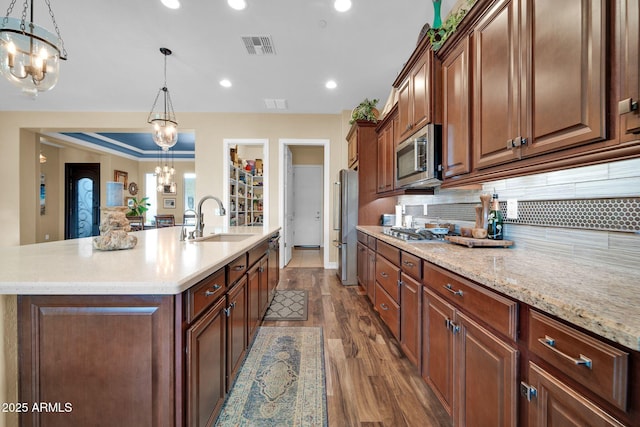 kitchen featuring appliances with stainless steel finishes, an island with sink, sink, hanging light fixtures, and a chandelier