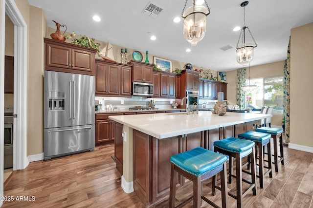 kitchen featuring a spacious island, pendant lighting, light wood-type flooring, a kitchen breakfast bar, and stainless steel appliances