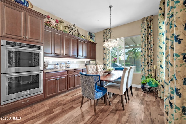 kitchen with decorative light fixtures, decorative backsplash, light hardwood / wood-style flooring, double oven, and a chandelier