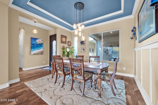 dining space featuring ornamental molding, dark hardwood / wood-style flooring, a raised ceiling, and a chandelier