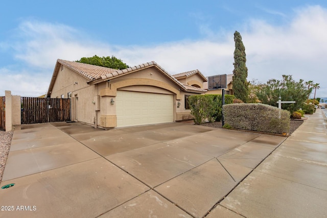 view of front of property with concrete driveway, a tiled roof, an attached garage, a gate, and stucco siding