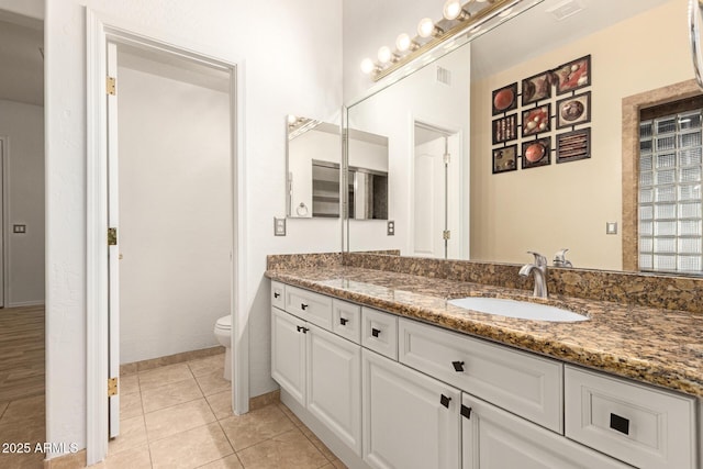 bathroom featuring visible vents, baseboards, toilet, tile patterned flooring, and vanity