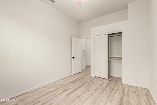 unfurnished bedroom featuring a closet, wood finished floors, visible vents, and baseboards