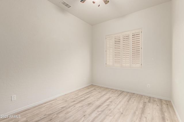 empty room with wood finished floors, visible vents, and baseboards