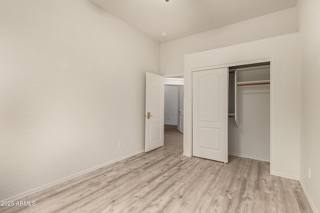 unfurnished bedroom with light wood finished floors, a closet, and baseboards