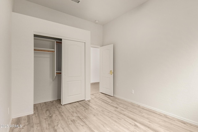 unfurnished bedroom featuring a closet, baseboards, and wood finished floors