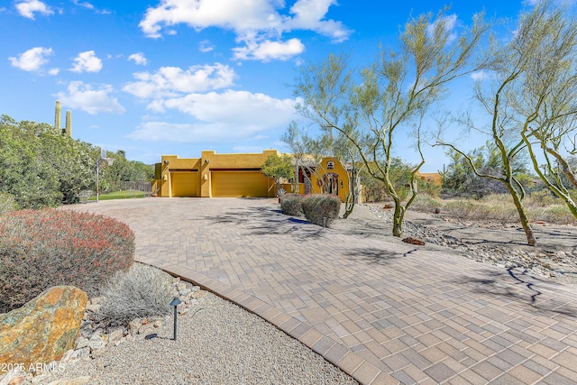 9415 N 124th St, Scottsdale, AZ 85259 - pueblo-style home featuring a garage, decorative driveway, and stucco siding