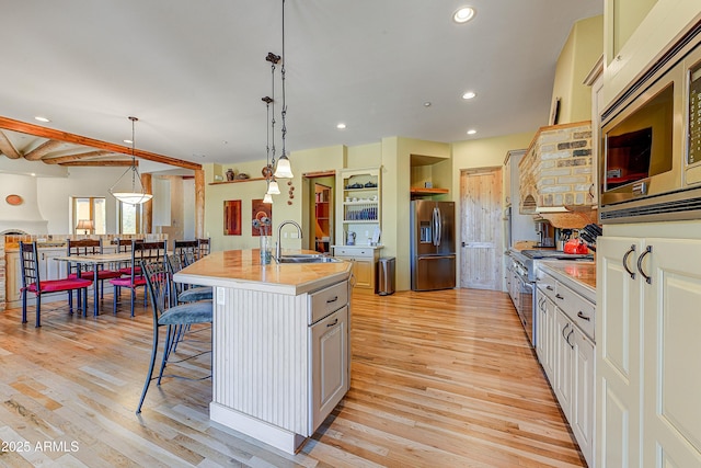 9415 N 124th St, Scottsdale, AZ 85259 - kitchen featuring appliances with stainless steel finishes, a sink, light countertops, light wood-style flooring, and a breakfast bar area