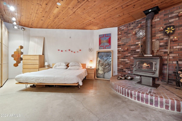 bedroom featuring a wood stove, concrete floors, and wooden ceiling