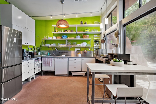 kitchen with sink, white cabinetry, decorative light fixtures, white dishwasher, and stainless steel fridge