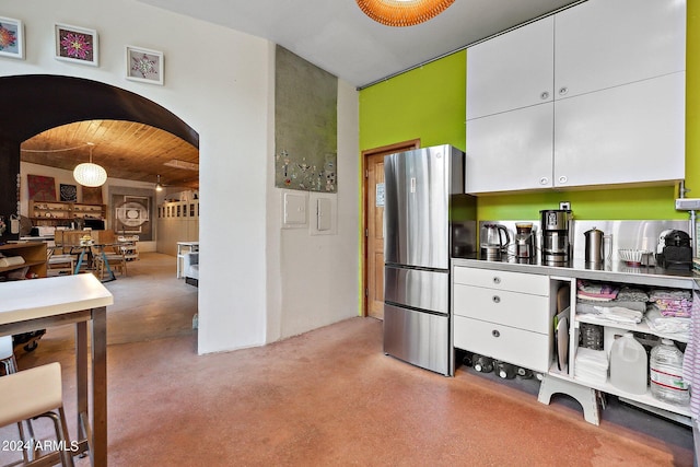 kitchen with white cabinets, wooden ceiling, stainless steel counters, and stainless steel fridge