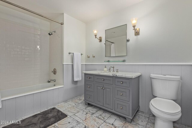 full bathroom featuring vanity, wainscoting, shower / tub combination, toilet, and marble finish floor