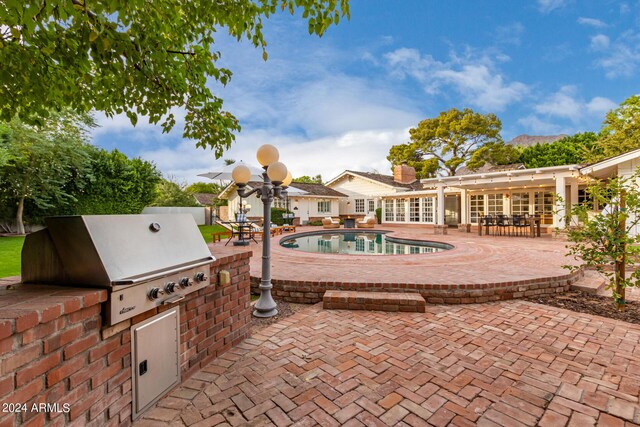 view of patio featuring area for grilling, an outdoor kitchen, french doors, and an outdoor pool