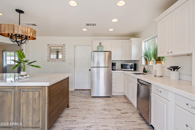 kitchen with visible vents, a sink, stainless steel appliances, white cabinets, and a healthy amount of sunlight