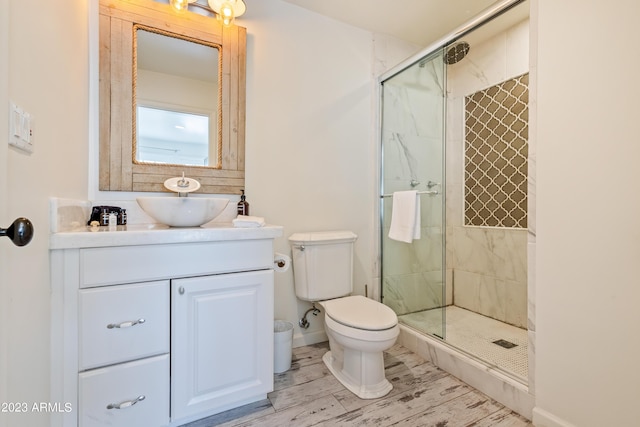 bathroom with vanity, wood finished floors, baseboards, a shower stall, and toilet