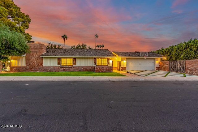 view of front of property with brick siding, fence, a lawn, driveway, and an attached garage