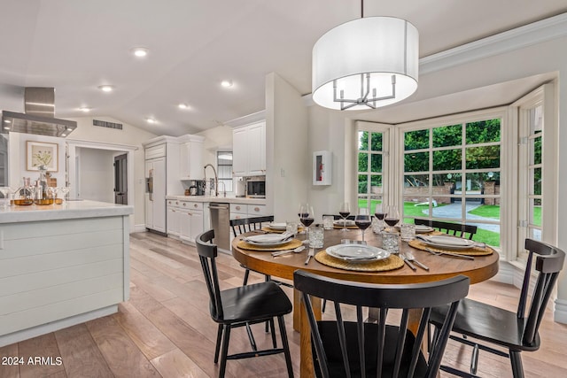 dining room with visible vents, a chandelier, vaulted ceiling, and light wood finished floors