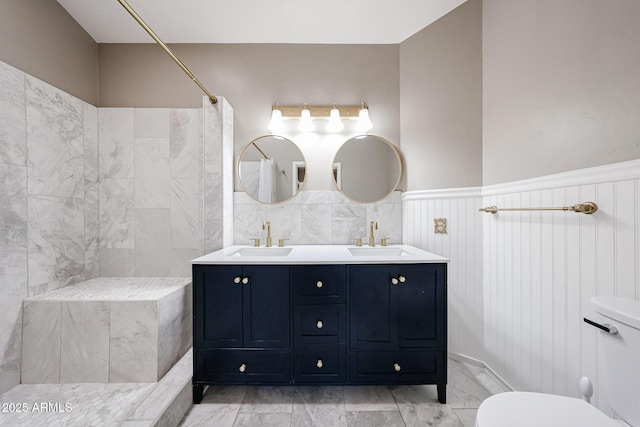 6533 N 7th Ave Unit 18, Phoenix, AZ 85013 - bathroom with marble look tiles, wainscoting, a tile shower, double vanity, and toilet