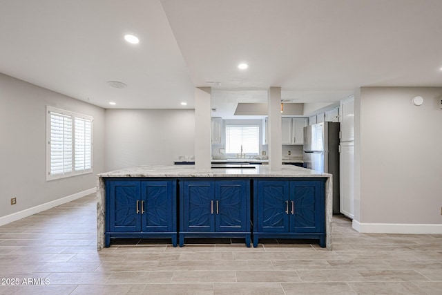 6533 N 7th Ave Unit 18, Phoenix, AZ 85013 - kitchen featuring freestanding refrigerator, blue cabinets, recessed lighting, light stone counters, and baseboards
