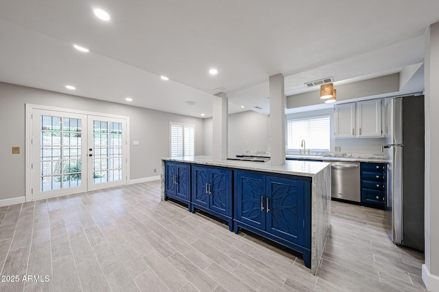 6533 N 7th Ave Unit 18, Phoenix, AZ 85013 - kitchen with appliances with stainless steel finishes, blue cabinets, a sink, baseboards, and a kitchen island