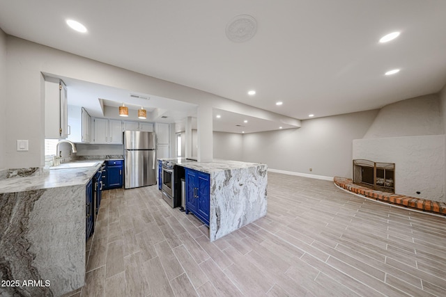 6533 N 7th Ave Unit 18, Phoenix, AZ 85013 - kitchen with blue cabinets, stainless steel appliances, a sink, baseboards, and light stone countertops