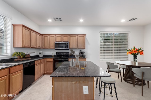 kitchen featuring black appliances, a center island, a breakfast bar, dark stone counters, and recessed lighting