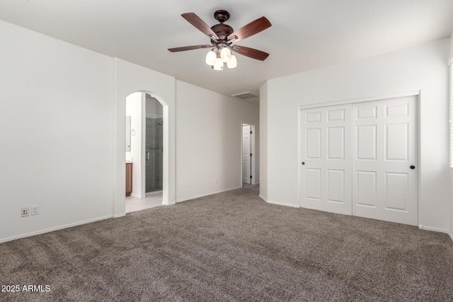 unfurnished bedroom featuring arched walkways, carpet floors, a closet, and baseboards