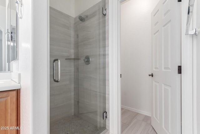 bathroom with vanity, a stall shower, and baseboards