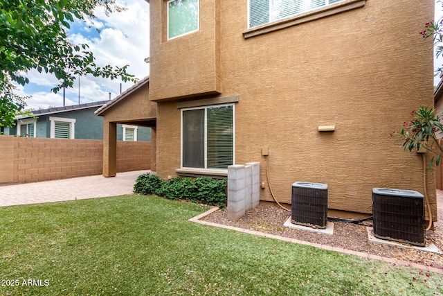 back of house with stucco siding, central air condition unit, and a patio
