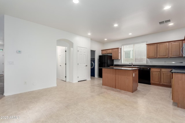 kitchen featuring black appliances, a center island, arched walkways, dark countertops, and recessed lighting