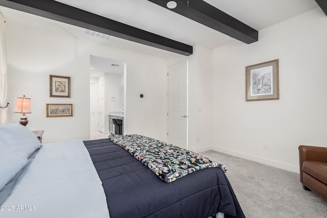 bedroom with carpet flooring, beam ceiling, and ensuite bathroom