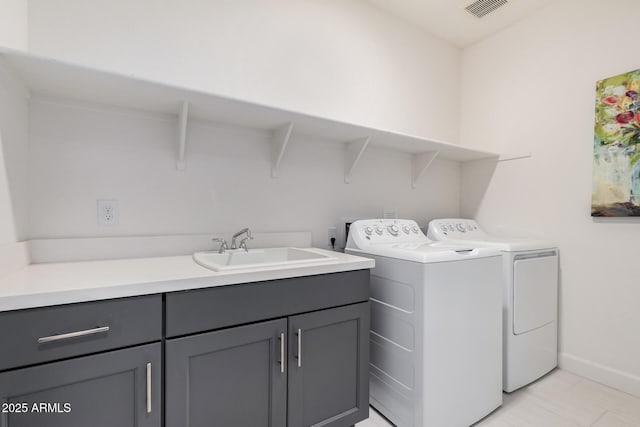 laundry room with cabinets, light tile patterned floors, sink, and washing machine and clothes dryer